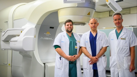 Team cardiologie en radiotherapie bij bestralingstoestel. Dr. Bert Vandenberk, Dr. Patrick Berkovic, en prof. dr. Joris Ector